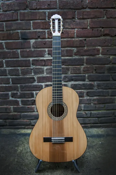 Cedar top classical guitar: front view against a brick wall