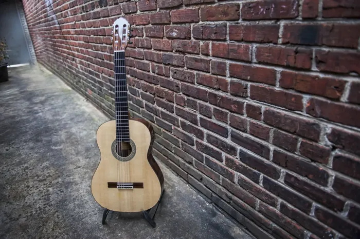 Spruce top classical guitar: wide view against a brick wall